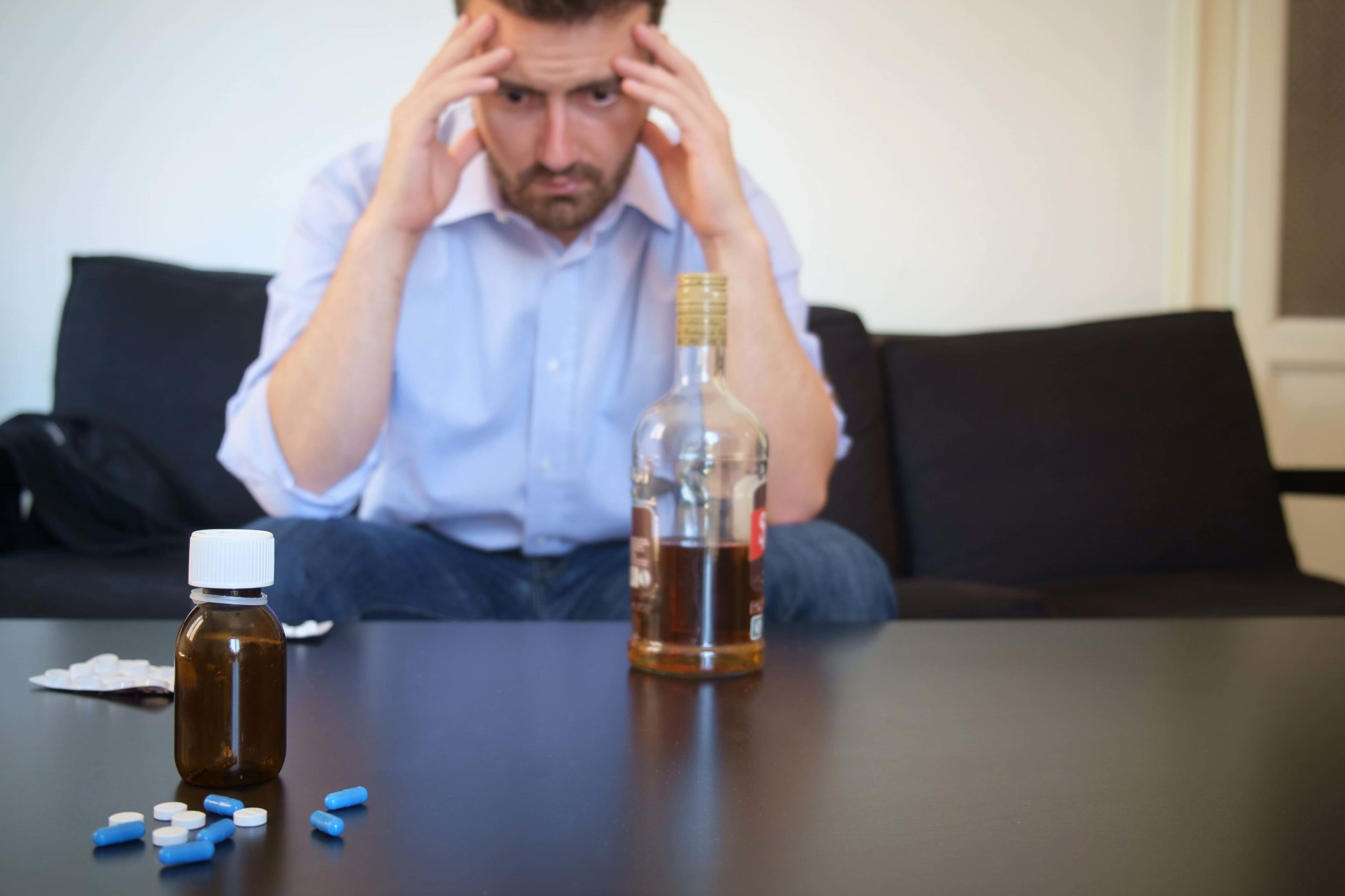 depressed man drinking alcohol and taking bipolar medications