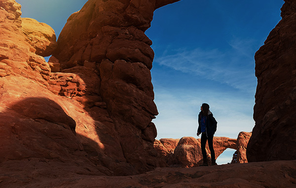 Person admiring rock arch formation