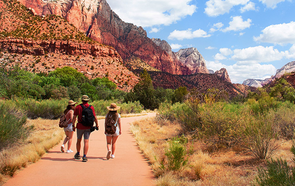 Three people walking down a southwestern trail